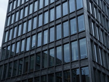 Geometric patterns of a modern office building facade reflecting a cool, overcast sky, deep blue and slate tones, architectural details, 35mm lens