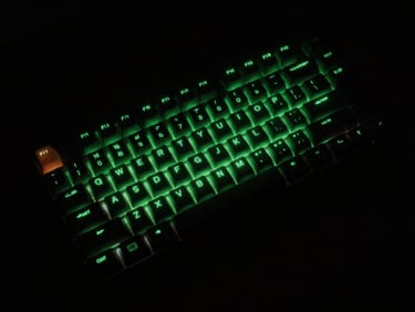 Overhead shot of a mechanical keyboard illuminated by a harsh green screen glow in a pitched black room.