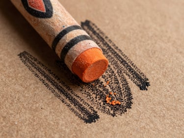 Close-up macro shot of wax crayon texture on raw brown craft paper, heavy black and earthy orange strokes showing the grain and physical friction of the medium