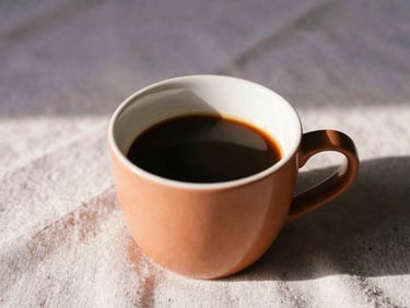 Close-up of a warm cup of coffee on a linen cloth, soft sunbeams, terracotta color accents.