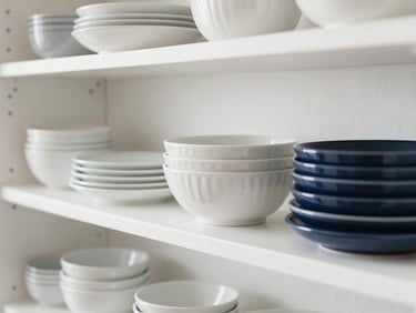 Organized modern kitchen shelves with premium ceramic dinnerware, soft natural daylight, clean white and navy tones, shallow depth of field, 35mm