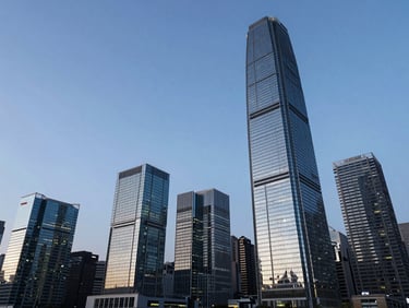 Wide-angle architectural shot of the Hong Kong Central skyline at blue hour, towering glass skyscrapers reflecting deep obsidian and cool cyan light, clean negative space on the left.