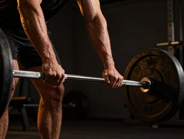Dynamic low-angle shot of a member gripping a knurled barbell under dramatic high-contrast gym lighting, warm amber glow on deep charcoal background.
