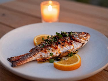 Artfully plated grilled red snapper with local herbs and citrus, served on a ceramic plate, warm ambient candlelight, shallow depth of field, 35mm