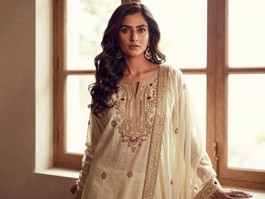 Indian female model in a flowing ethnic wear outfit, rich embroidery details, warm editorial fashion photography, soft natural window light