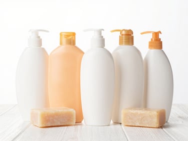Neat arrangement of shampoo bottles and soap bars on a white surface, high-key lighting