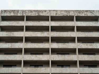 Close-up architectural detail of a well-finished Chennai apartment building facade — overcast daylight, straight-on human eye-level framing, concrete balconies and window reveals showing material quality, no people, no staging