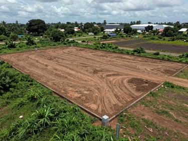 Overhead view of a cleared land plot boundary in Oragadam, Chennai, overcast light, survey stones visible at corners, industrial growth zone visible in background