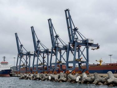 Overcast wide shot of a port terminal with heavy cranes and concrete breakwaters, industrial maritime setting, technical composition