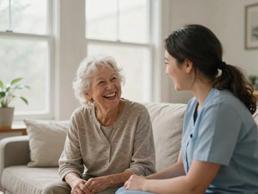 A caregiver and a senior client sharing a quiet moment of laughter in a comfortable, sunlit Indianapolis living room, soft natural light, shallow depth of field, 35mm warm editorial photography.