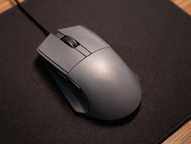 Top-down studio shot of a gaming mouse on a matte dark mousepad, clinical even lighting revealing sensor housing and side-button detail, neutral steel tones, no dramatic shadows