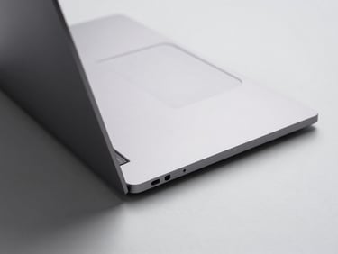Top-down studio shot of an ultrabook laptop on a light gray surface, thin profile visible at the hinge, even shadowless studio lighting showing premium chassis