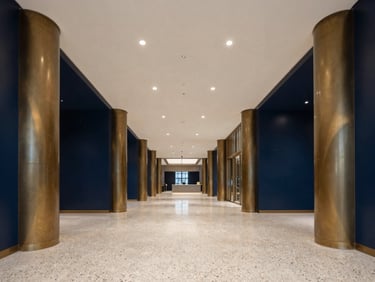 Symmetrical grand commercial lobby with polished terrazzo floors and bronze pillars, crisp interior lighting, 35mm architectural photography
