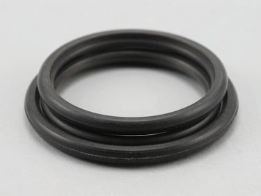 Close-up macro shot of industrial black rubber gaskets and O-rings with clean edges, stacked neatly on a neutral light gray background, bright high-key studio lighting, crisp details