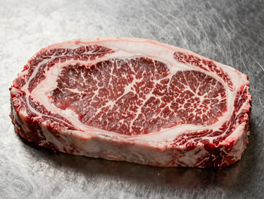 Tight overhead close-up of a fresh beef sirloin cut on a clean stainless steel surface under studio daylight — showing surface texture, deep red color, and fat marbling, no styling