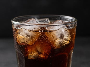 Cold refreshing soda glass with condensation, ice cubes, dark moody background, dramatic side lighting.