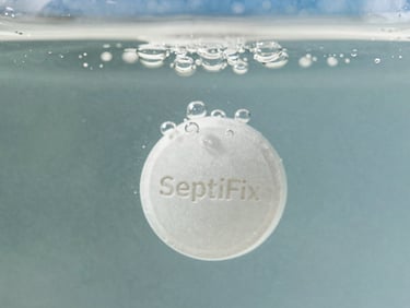 Macro shot of a white SeptiFix tablet effervescing in clear water, releasing tiny oxygen bubbles, bright studio lighting, crisp focus.