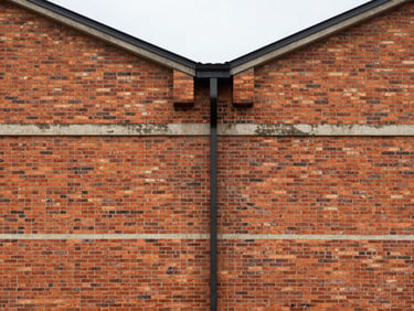Symmetrical architectural shot of a brick warehouse exterior, clean mortar lines, overcast daylight.