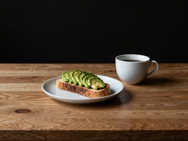 Minimalist table setting with a plate of avocado toast and a cup of coffee, warm wood texture, high-contrast side-lighting, 35mm lens.