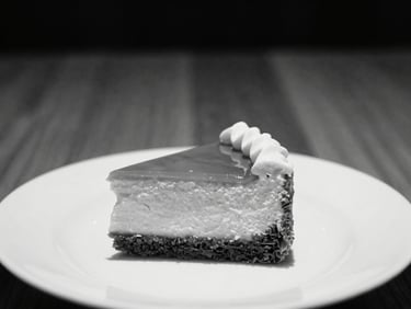 Close-up of a beautifully presented dessert on a minimalist plate, high-contrast monochrome, warm wood background, 35mm lens.