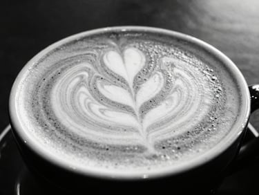 Close-up of a freshly pulled latte with intricate foam art, minimalist monochrome setting, high-contrast lighting, 35mm lens.
