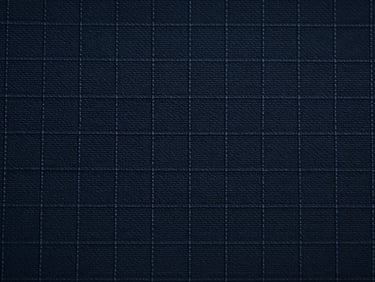 Macro flat-overhead close-up of ripstop technical textile under cool studio strobe, grid reinforcement weave pattern in sharp focus, dark navy tone, no garments