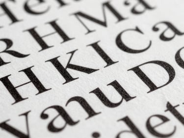Extreme close-up of a typographic system printed on uncoated white paper — letterforms in black ink, tight crop showing ink texture and fine serif details under even studio light, no distractions