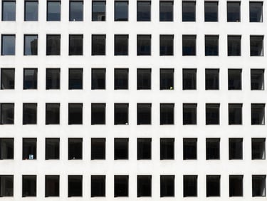 Modern building facade, high-contrast architectural shot, straight-on symmetrical composition, bright natural daylight, clean high-contrast tones