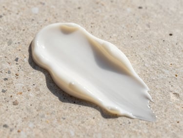 Close-up of a smooth cream swatch of physical sunscreen on a neutral stone background, soft natural daylight