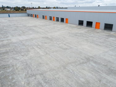 Aerial view of a vast, newly stripped and cleaned concrete floor inside a 10,000 m² industrial logistics warehouse in Dunkerque, bright uniform lighting, empty and ready for operations.
