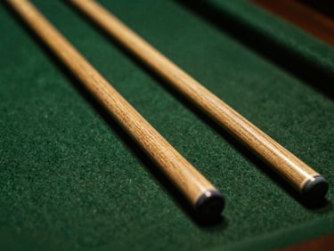 Macro shot of hand-turned wooden cue shafts resting on a dark felt surface, warm brass accents reflecting dramatic overhead light.