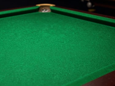 Close-up of pristine West of England wool cloth on a snooker table, shallow depth of field, dramatic overhead lighting casting rich green tones