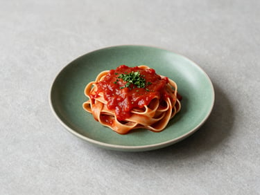 A minimalist Scandinavian table setting with a single plate of fresh pasta, deep tomato red sauce, matte green herb garnish, soft daylight shadows