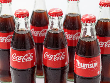 Close-up of chilled glass bottles of Coca-Cola and Thums Up with condensation, bright commercial food photography, sharp focus, 35mm
