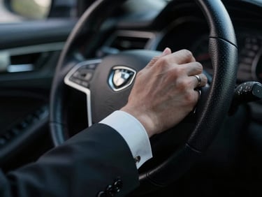 Extreme close-up of a tailored chauffeur cuff adjusting a steering wheel, low-key cinematic lighting, silver reflections, shallow depth of field