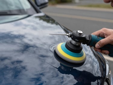 Close-up macro shot of a technician using a dual-action polisher on a caravan gelcoat, high-contrast reflections, crisp overcast daylight, 35mm.