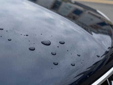 Macro shot of water beads forming perfect tight spheres on a freshly polished and protected caravan paint surface, high-contrast reflections, premium automotive feel, 35mm