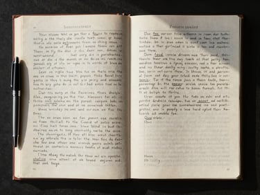 Overhead flat-lay of open manuscript pages, a fountain pen resting at the margin, north-facing natural light casting clean shadows across handwritten annotations and printed text blocks