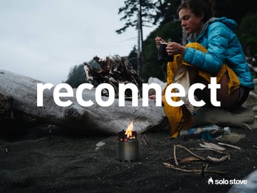 Woman sitting on the beach with small Solo Stove 