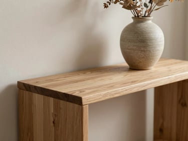 Intimate 45-degree close-up vignette of a light oak console table, a handmade ceramic vase holding dry foliage, soft diffused morning light, warm neutral tones.