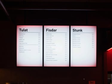 Straight-on architectural shot of a glowing digital menu board behind a modern cafe counter, soft red glow, dark background