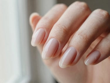 Macro close-up of elegant almond-shaped Gel-X nails with a minimalist blush nude finish, soft lighting