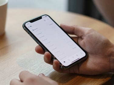Professional's hand gripping an Android phone on a café table, natural diffused light, screen displaying a time-tracking app with minimal chrome and clear numeric readout, tight crop