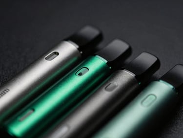 Macro shot of premium disposable vape devices, sleek metallic finishes with subtle emerald green highlights, dramatic low-key lighting, 35mm