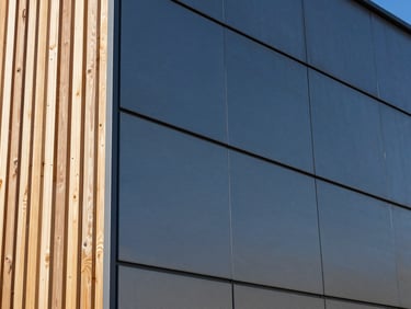 Close-up of a building's exterior showcasing a textured aluminum cladding panel next to a natural wooden slat, emphasizing clean lines and material quality.
