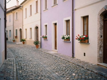 Cobblestone alleyway in a historic Italian village, soft pastel buildings, potted flowers, warm afternoon sun, shallow depth of field, 35mm film.