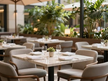Sunlit outdoor restaurant terrace of a boutique hotel, clean modern tables, lush green foliage in the background, soft warm lighting.