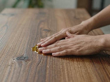 Close-up of hands applying natural oil to rich, textured weathered teak timber, soft morning light, shallow depth of field