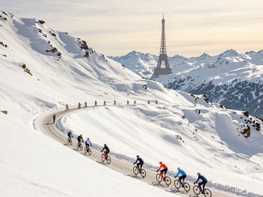 Scenic view of road cyclists climbing a steep mountain pass in the French Alps, with a distant view of the Eiffel Tower in the soft golden sky, sunny daylight.