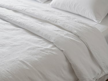 Tactile close-up of perfectly ironed, crisp white high-thread-count cotton bed linen, soft natural side light highlighting the weave and delicate texture, luxurious and serene atmosphere.